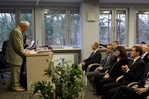 Mężczyzna przemawiający z mównicy przed uczestnikami spotkania jubileuszowego.