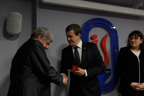 Uścisk dłoni i wręczenie odznaczenia pracownikowi w obecności dyrekcji.