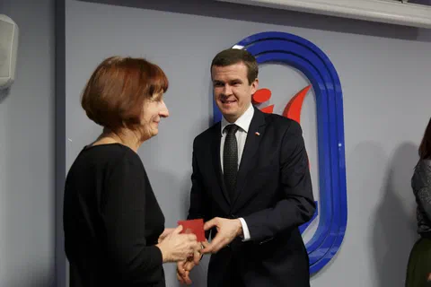 Gratulacje i przekazanie odznaczenia w etui pracownicy podczas spotkania jubileuszowego.