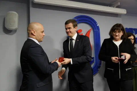 Przekazanie odznaczenia w etui pracownikowi w garniturze.