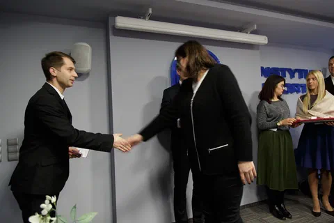 Gratulacje i uścisk dłoni przy wręczaniu dyplomu młodemu pracownikowi.
