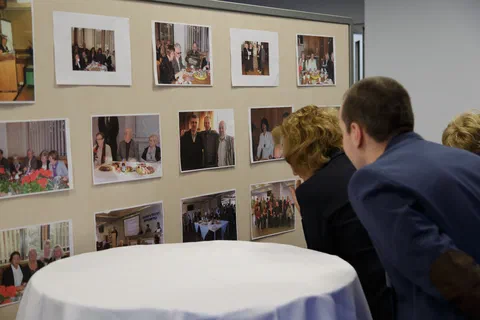 Uczestnicy spotkania oglądający tablicę z archiwalnymi fotografiami z historii Instytutu.