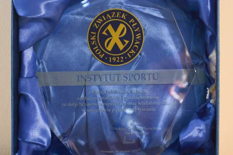 Szklana statuetka okolicznościowa od Polskiego Związku Pływackiego w granatowym etui.