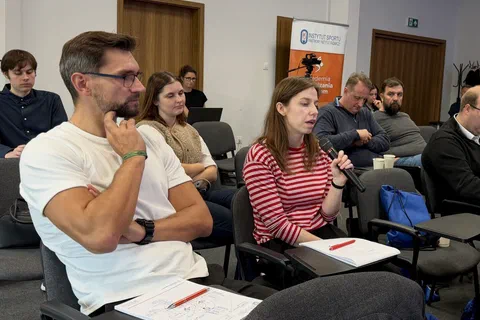 Uczestniczka siedząca na widowni i zabierająca głos przez mikrofon podczas dyskusji.