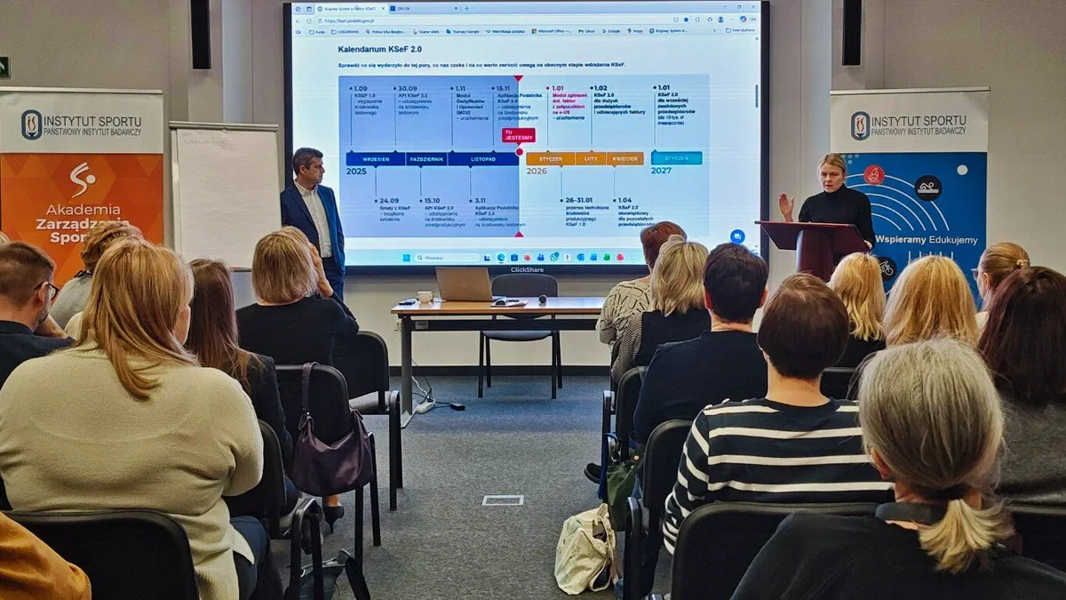 Prowadzący omawiający prezentację podczas szkolenia Akademii Zarządzania Sportem o cyfryzacji rachunkowości i podatków przed uczestnikami w sali wykładowej.