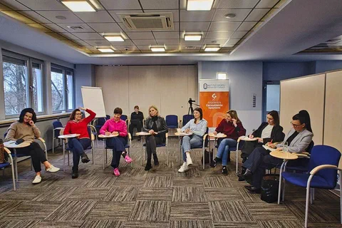 Uczestniczki warsztatów siedzące w półkolu i notujące na kartach ćwiczeniowych.