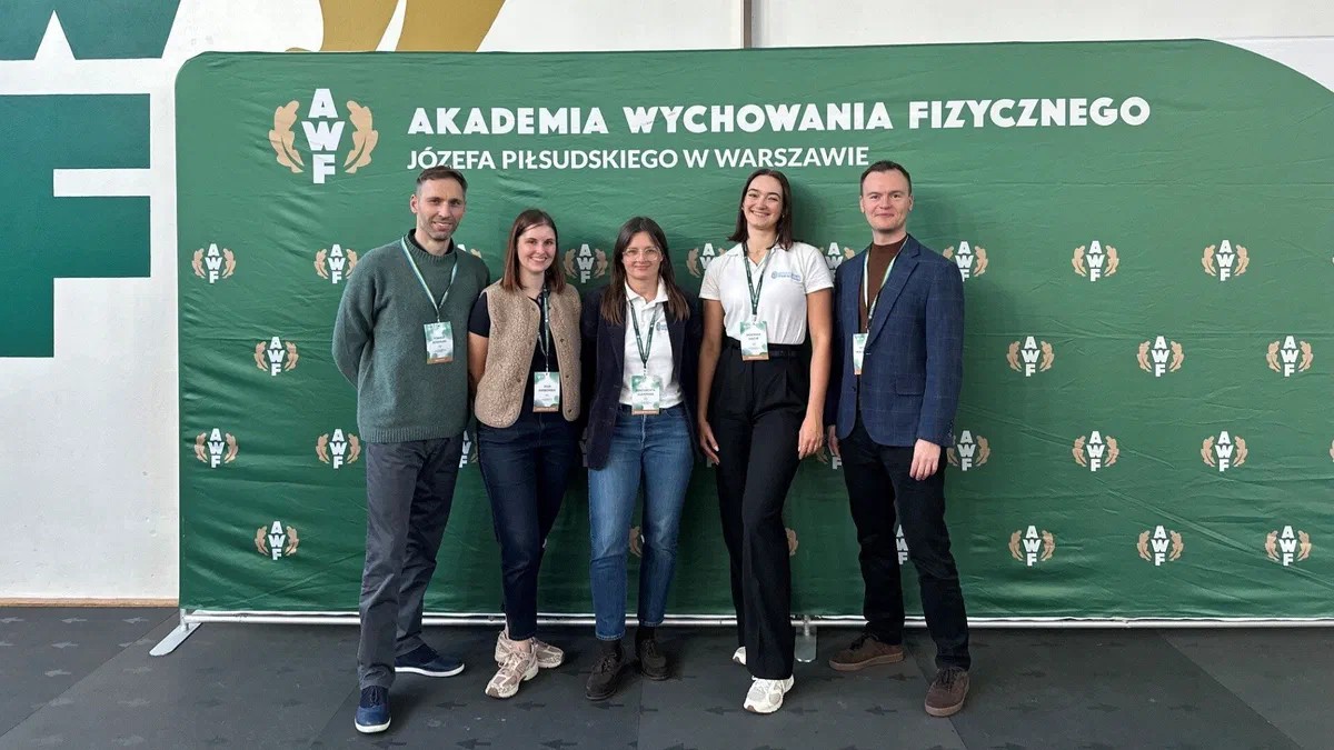 Pięcioro prelegentów z Instytutu Sportu – PIB na tle ścianki Akademii Wychowania Fizycznego Józefa Piłsudskiego w Warszawie podczas konferencji „Człowiek – Sportowiec – Mistrz”.