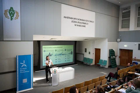 Prelegentka wygłaszająca referat z mównicy w auli wykładowej Akademii Wychowania Fizycznego w Warszawie.