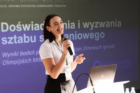 Prelegentka w białej koszulce przemawiająca na tle slajdu o doświadczeniach i wyzwaniach sztabu szkoleniowego.