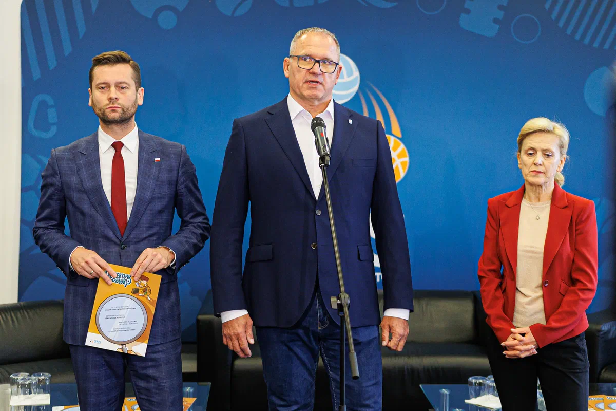 Trzy osoby na scenie podczas inauguracji akcji „Sportowa Przygoda z Detektywem Zdrówko” programu Szkolny Klub Sportowy w hali COS Torwar.