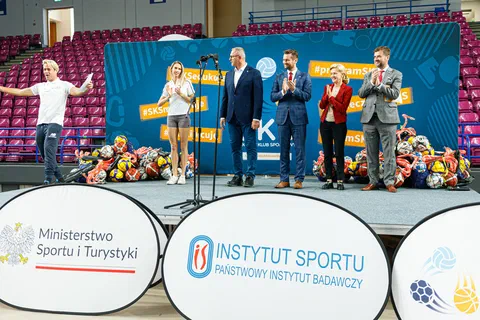 Goście i sportowcy klaszczący na scenie za bandami z logotypami Ministerstwa Sportu i Turystyki oraz Instytutu Sportu – PIB.