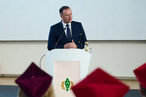 Mężczyzna w ciemnym garniturze przemawiający z mównicy podczas uroczystości.