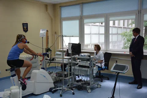 Pokaz próby wysiłkowej zawodniczki w masce pomiarowej na cykloergometrze w pracowni fizjologii.