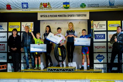 Trzej młodzi kolarze na podium z pucharami i bonami na badania w Instytucie Sportu – PIB.