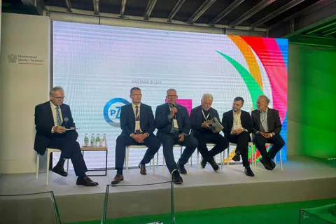Pięciu uczestników panelu dyskusyjnego siedzących w fotelach na scenie przed kolorowym ekranem kongresu.