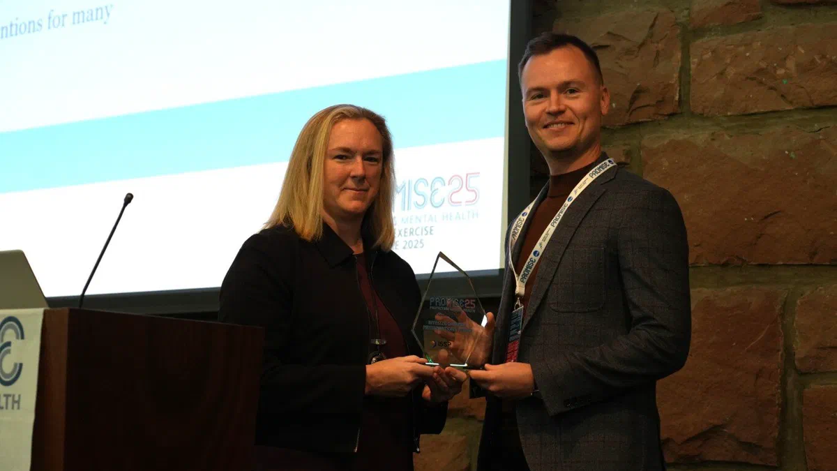 Dr Wojciech Waleriańczyk odbierający pamiątkową statuetkę z rąk organizatorki podczas konferencji „Protecting Mental Health in Sport + Exercise”.