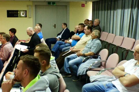 Trenerzy i uczestnicy konferencji słuchający wykładu na widowni.