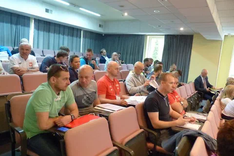 Widok z boku na rzędy krzeseł wypełnione uczestnikami konferencji w sali wykładowej.