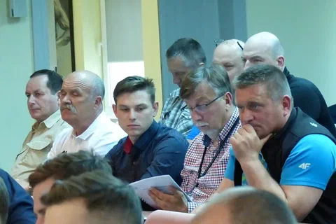 Uczestnicy na widowni przeglądający materiały konferencyjne podczas sesji.