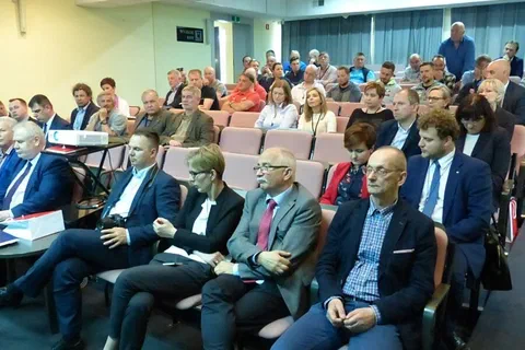 Szeroki kadr widowni z uczestnikami siedzącymi w sali konferencyjnej.