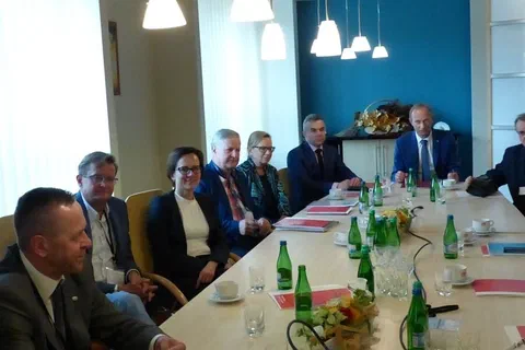 Spotkanie robocze uczestników siedzących przy długim stole konferencyjnym.