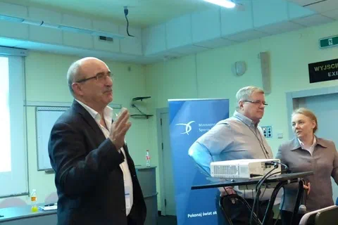 Dyskusja uczestnika z wykładowcą w obecności tłumaczki w sali konferencyjnej.