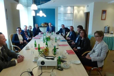 Widok z góry na uczestników spotkania siedzących wokół długiego stołu obrad.