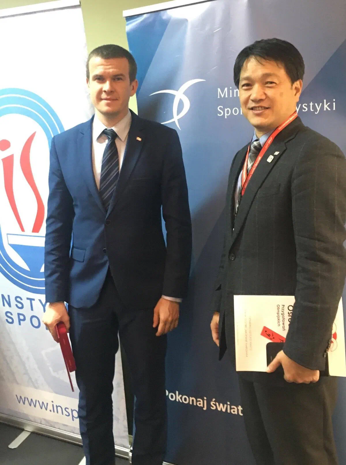 Dwaj uczestnicy Konferencji Trenerów Szkolenia Olimpijskiego „Tokyo 2020” na tle roll-upów Instytutu Sportu – PIB.