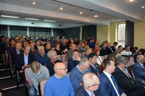Licznie zgromadzeni uczestnicy konferencji siedzący na widowni sali wykładowej.
