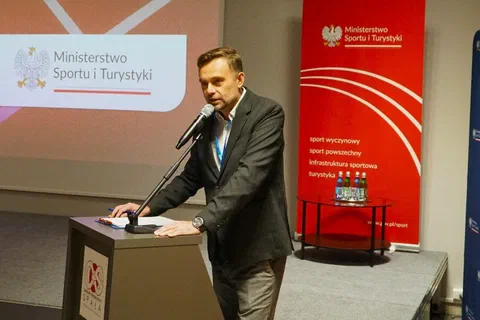 Wystąpienie z mównicy COS Spała na tle ekranu i banerów Ministerstwa Sportu i Turystyki.