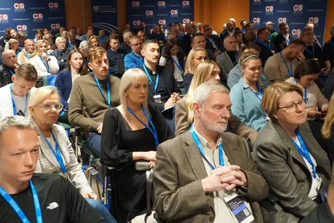 Uczestnicy konferencji z identyfikatorami siedzący na widowni sali wykładowej.