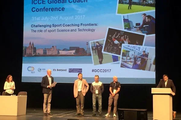 Prelegenci na scenie konferencji ICCE Global Coach Conference 2017 w Liverpoolu przed dużym ekranem projekcyjnym.