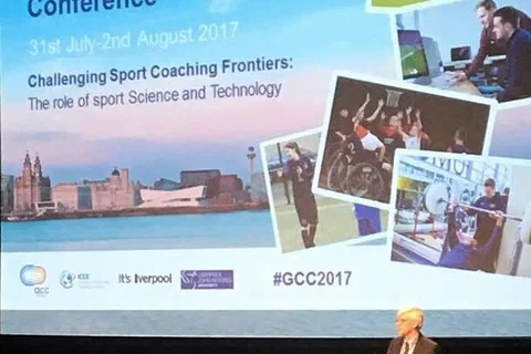 Prelegent przemawiający przy mównicy pod dużym ekranem powitalnym 11. konferencji ICCE Global Coach Conference
