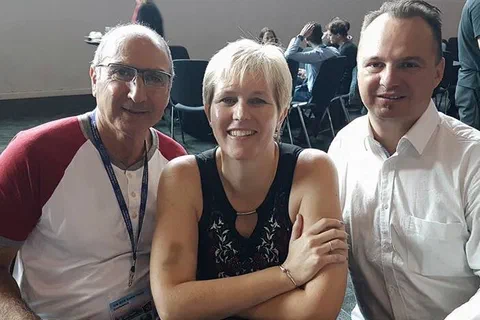 Trójka uczestników konferencji pozująca przy stoliku w przerwie obrad