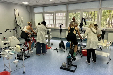 Zawodnicy wykonujący próbę wysiłkową na cykloergometrach pod nadzorem personelu w laboratorium
