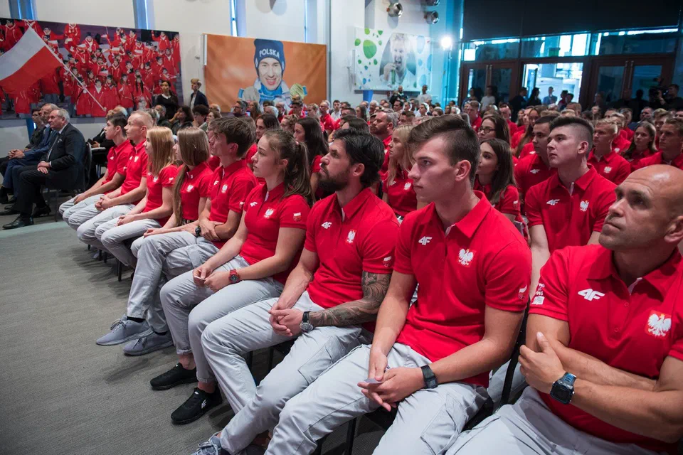 Młodzi sportowcy w strojach reprezentacyjnych siedzący na widowni sali konferencyjnej Centrum Olimpijskiego PKOl podczas uroczystości wręczenia nominacji