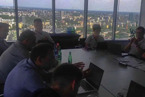 Eksperci pracujący z laptopami przy dużym stole konferencyjnym na tle wieczornej panoramy miasta za oknem