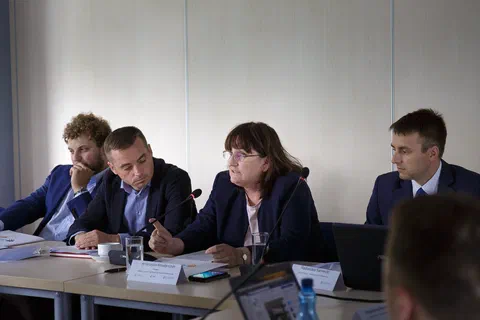 Kobieta przy stole prezydialnym zabierająca głos w obecności trzech mężczyzn