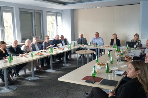 Członkowie Rady Naukowej siedzący przy stołach ustawionych w podkowę podczas posiedzenia w sali konferencyjnej