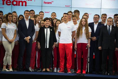Wspólne zdjęcie przedstawicieli instytucji i grupy zawodników w biało-czerwonych strojach na scenie
