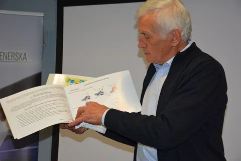 Wykładowca pokazujący uczestnikom otwartą publikację z ilustracjami ćwiczeń sportowych
