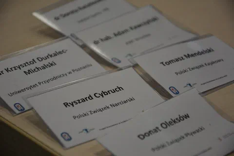 Rozłożone na stole identyfikatory uczestników szkolenia z nazwami polskich związków sportowych
