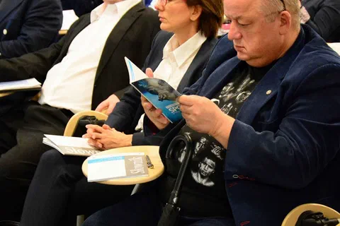 Pionowy kadr uczestników czytających broszury informacyjne podczas pracy w grupie