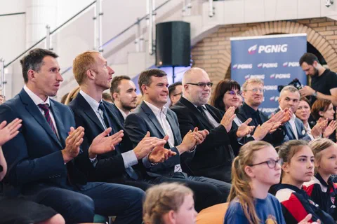 Goście oficjalni i młodzi sportowcy klaszczący na widowni podczas uroczystości