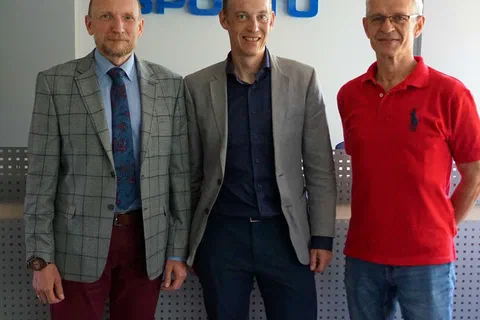 Pionowy kadr trzech mężczyzn stojących przed napisem Instytut Sportu w sali konferencyjnej