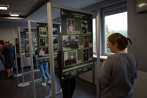 Kobieta na pierwszym planie czytająca tablicę z fotografiami z historii reprezentacji piłkarskiej