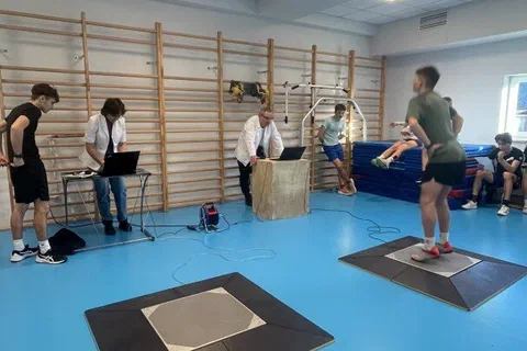 Szeroki kadr sali z dwoma stanowiskami platform pomiarowych podczas badań skoczności młodych sportowców
