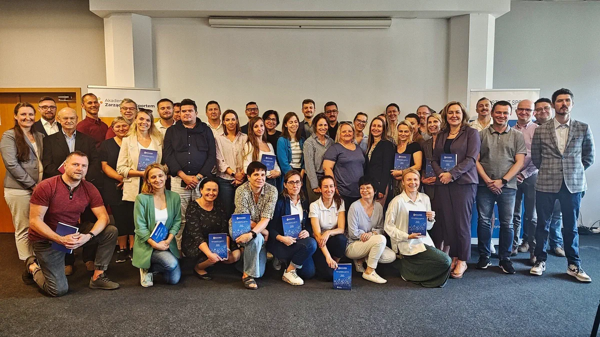 Grupowe zdjęcie uczestników prezentacji poradnika „Dane osobowe w sporcie” trzymających egzemplarze publikacji w sali konferencyjnej COS Torwar.