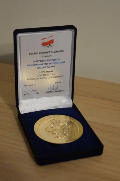 Złoty Medal Polskiego Komitetu Olimpijskiego „Za zasługi dla polskiego ruchu olimpijskiego” przyznany Instytutowi Sportu – Państwowemu Instytutowi Badawczemu w otwartym etui.