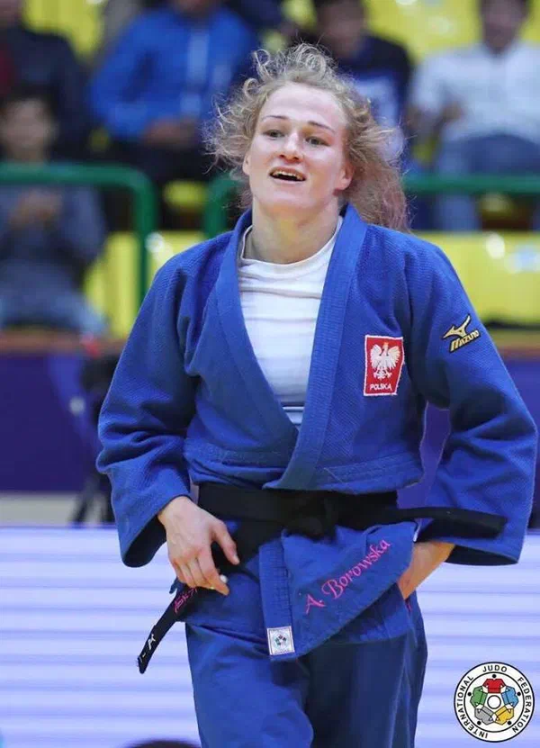 Dżudoczka Anna Borowska w niebieskim kimonie z godłem Polski na macie podczas zawodów.